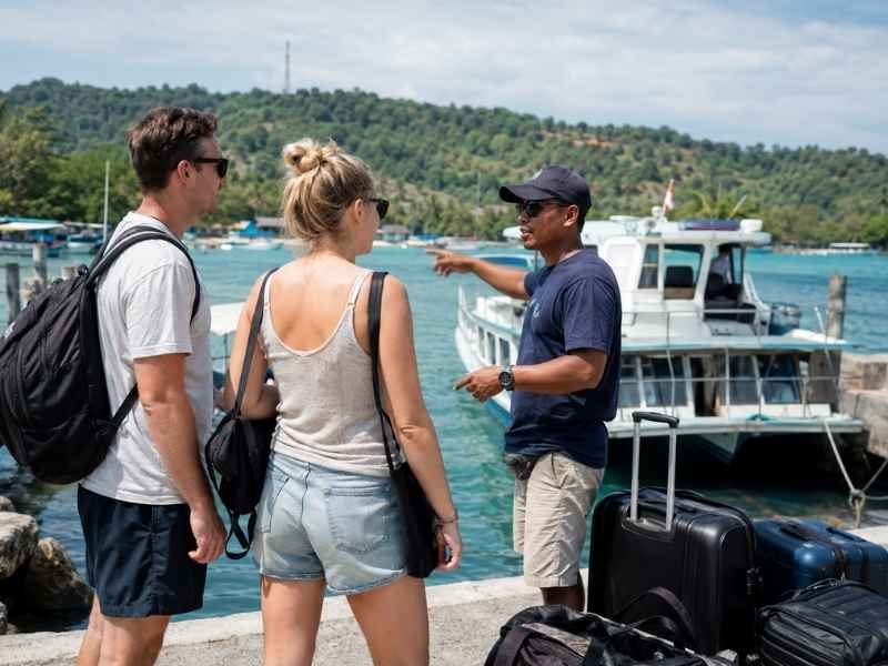 Local guide helping travelers plan a boat transfer at a Lombok harbor